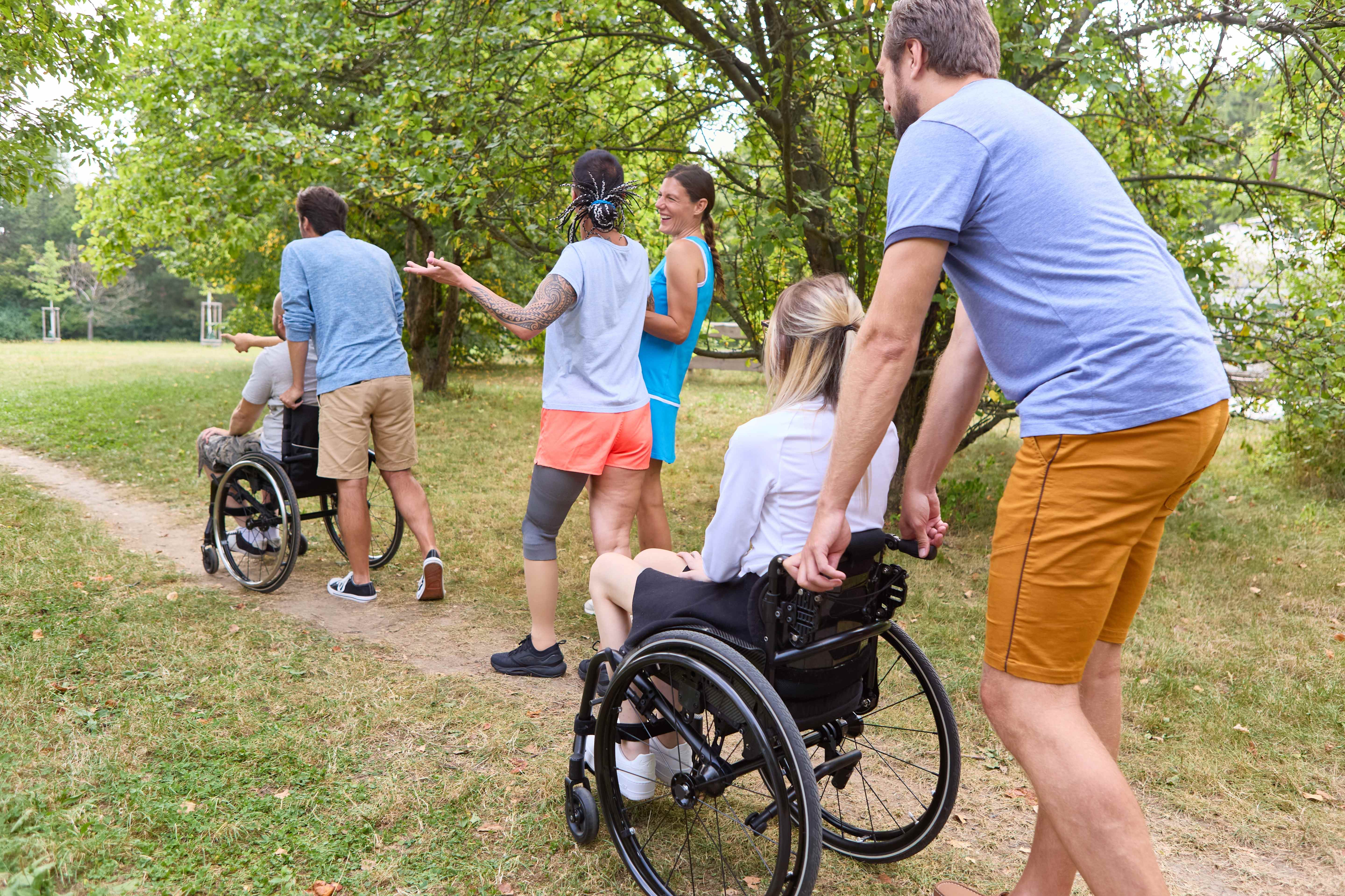 Diverse group including wheelchair users enjoying outdoor recreational activities in park setting