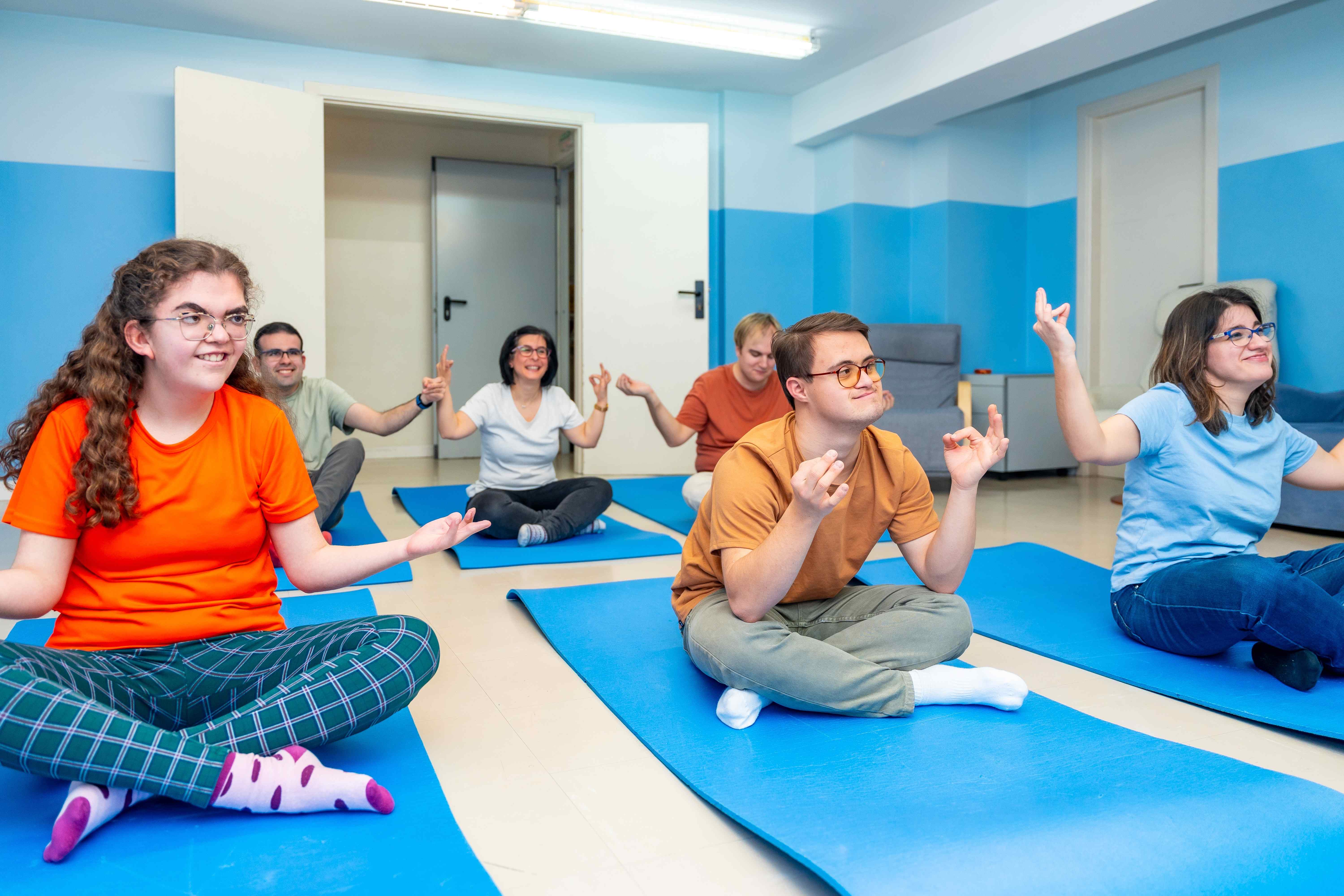 Group of people with intellectual disabilities participating in yoga session, all smiling and engaged